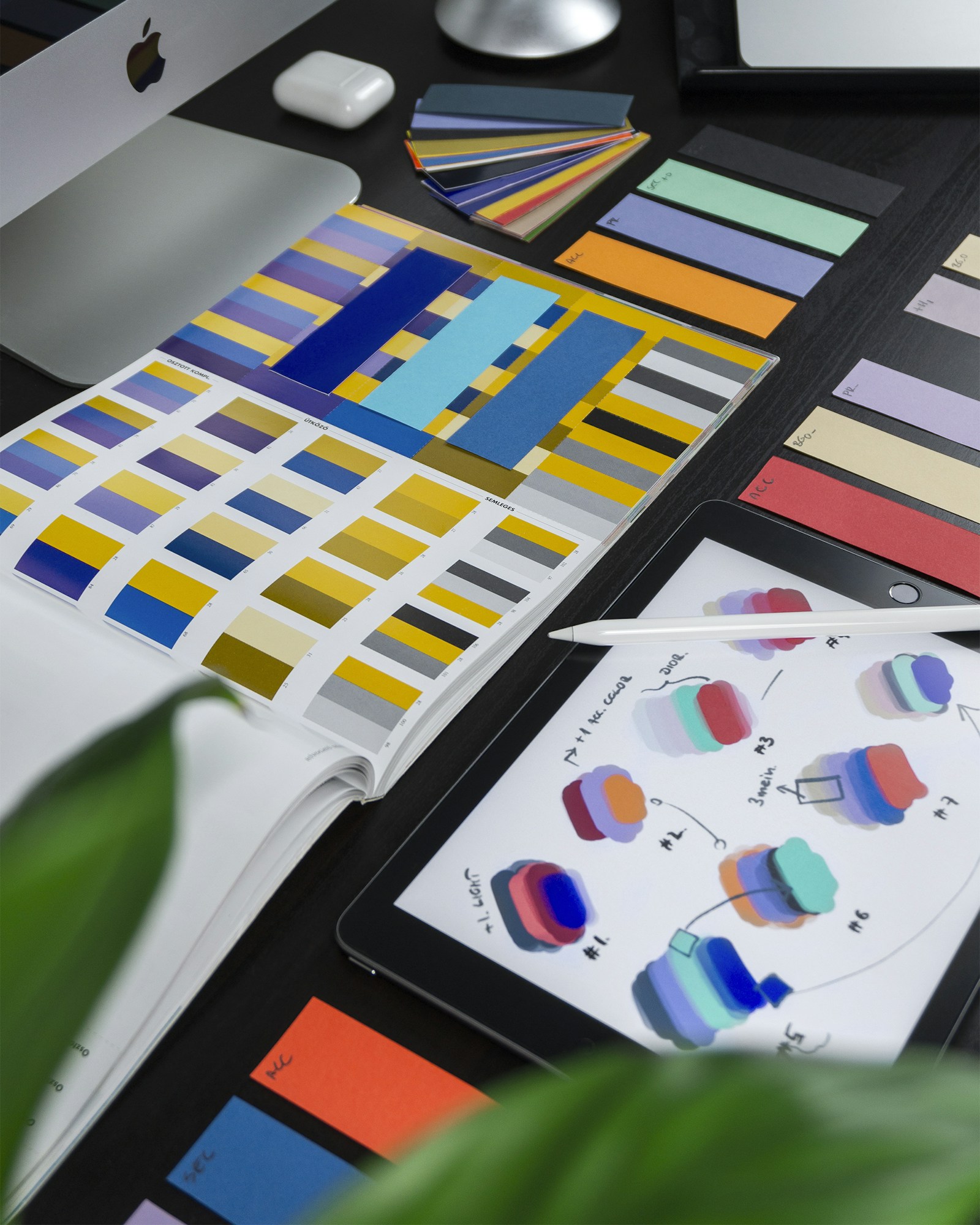Graphic-design workspace with color swatches, printed palettes and digital concept sketches